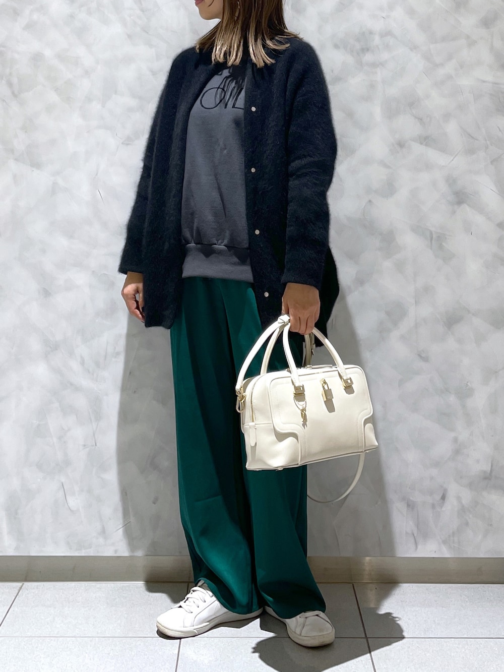 ホワイト系のハンドバッグ、ブラック系のカーディガン/ボレロを着用したレディースの冬コーディネートの2枚目の写真