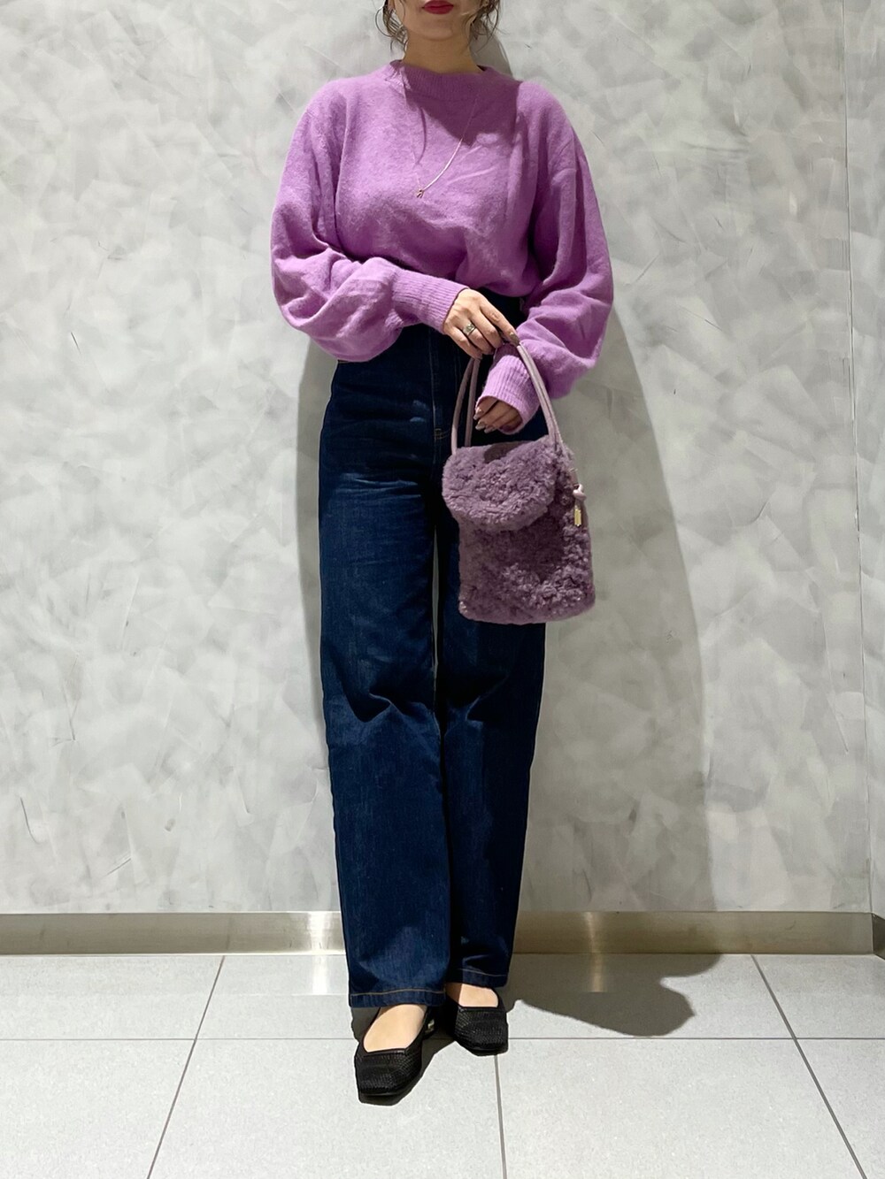 ブルー系のデニムパンツ、ブラック系のパンプス、パープル系のショルダーバッグを着用したレディースの秋コーディネートの3枚目の写真