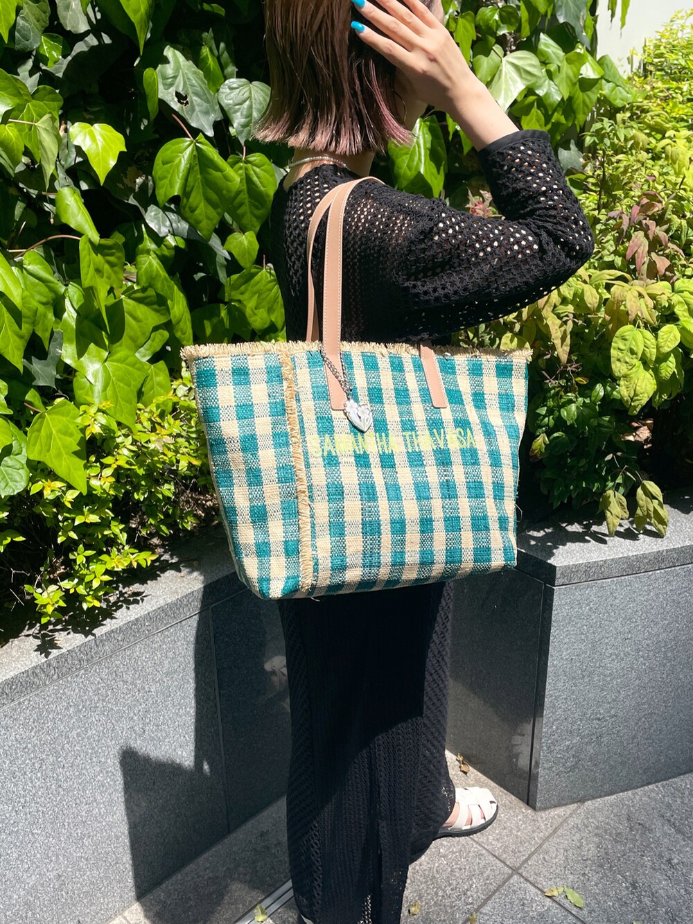 グリーン系のトートバッグ、ブラック系のワンピース、ブラック系のサンダルを着用したレディースの春コーディネートの3枚目の写真