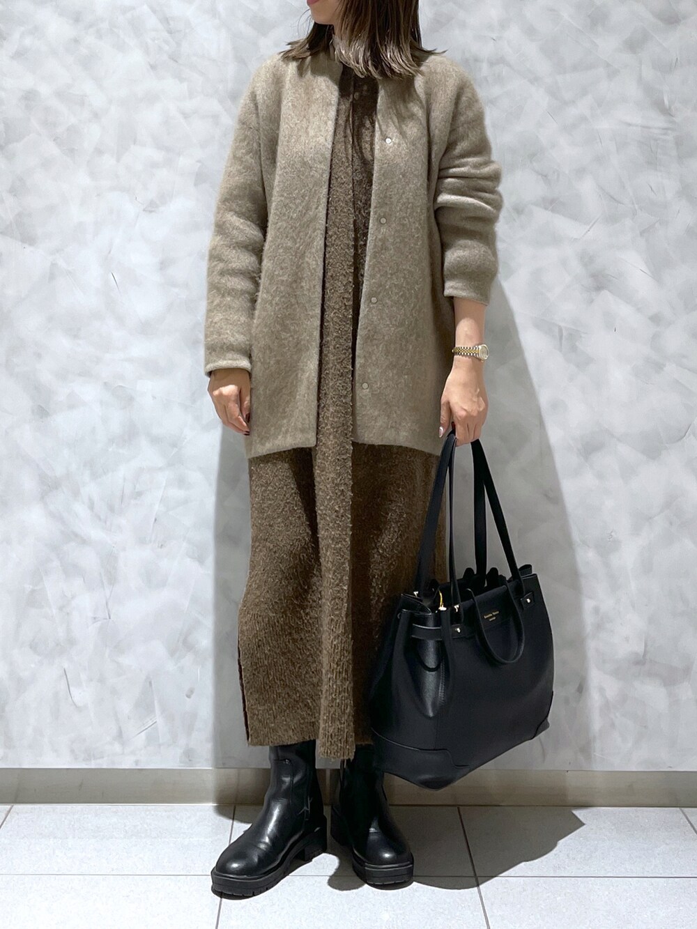 ブラック系のトートバッグ、ブラウン系のワンピース、ベージュ系のカーディガン/ボレロを着用したレディースの冬コーディネートの2枚目の写真