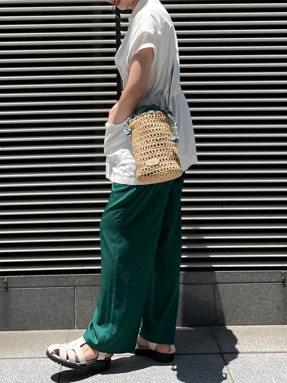 ブラック系のサンダル、グリーン系のその他パンツ、ピンク系のショルダーバッグを着用したレディースの夏コーディネートの2枚目の写真