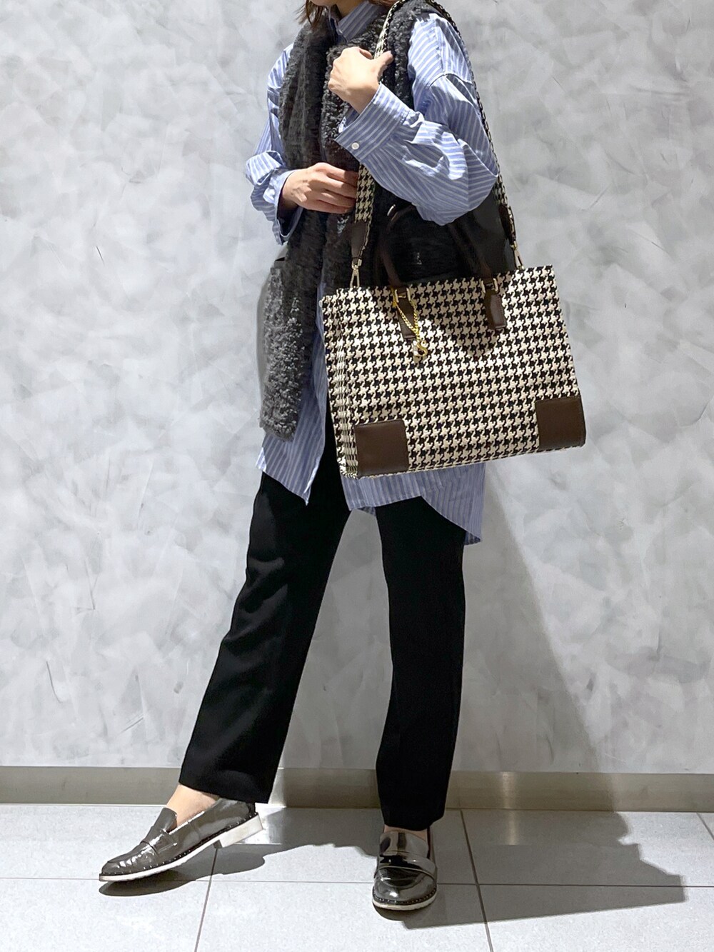 ブラウン系のトートバッグ、ブルー系のシャツ/ブラウス、グレー系のベストを着用したレディースの秋コーディネートの2枚目の写真