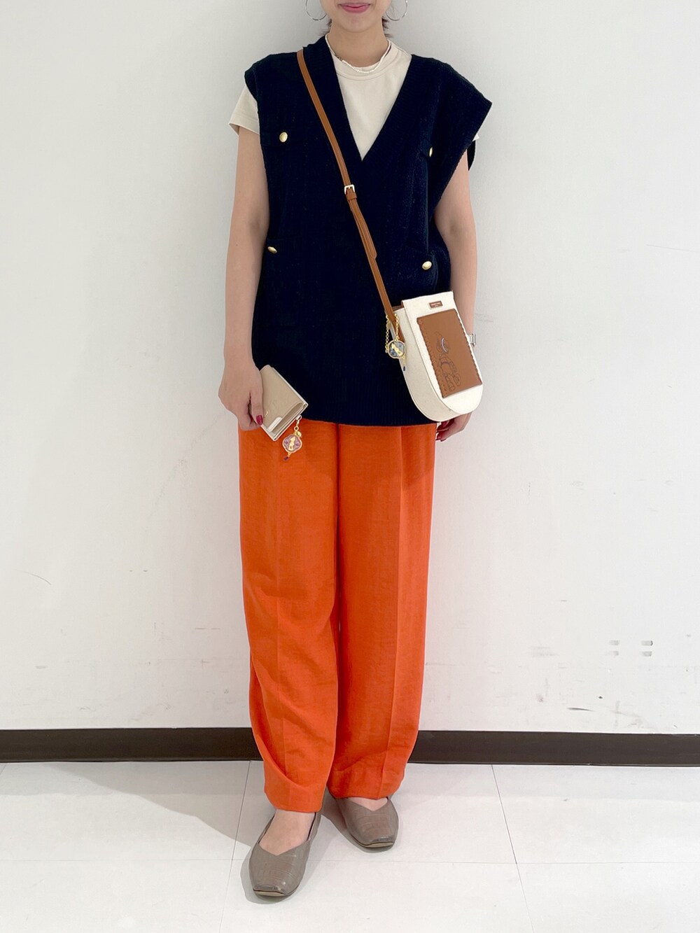ブラウン系のショルダーバッグ、オレンジ系のスラックス、ブルー系のベストを着用したレディースの秋コーディネートの3枚目の写真