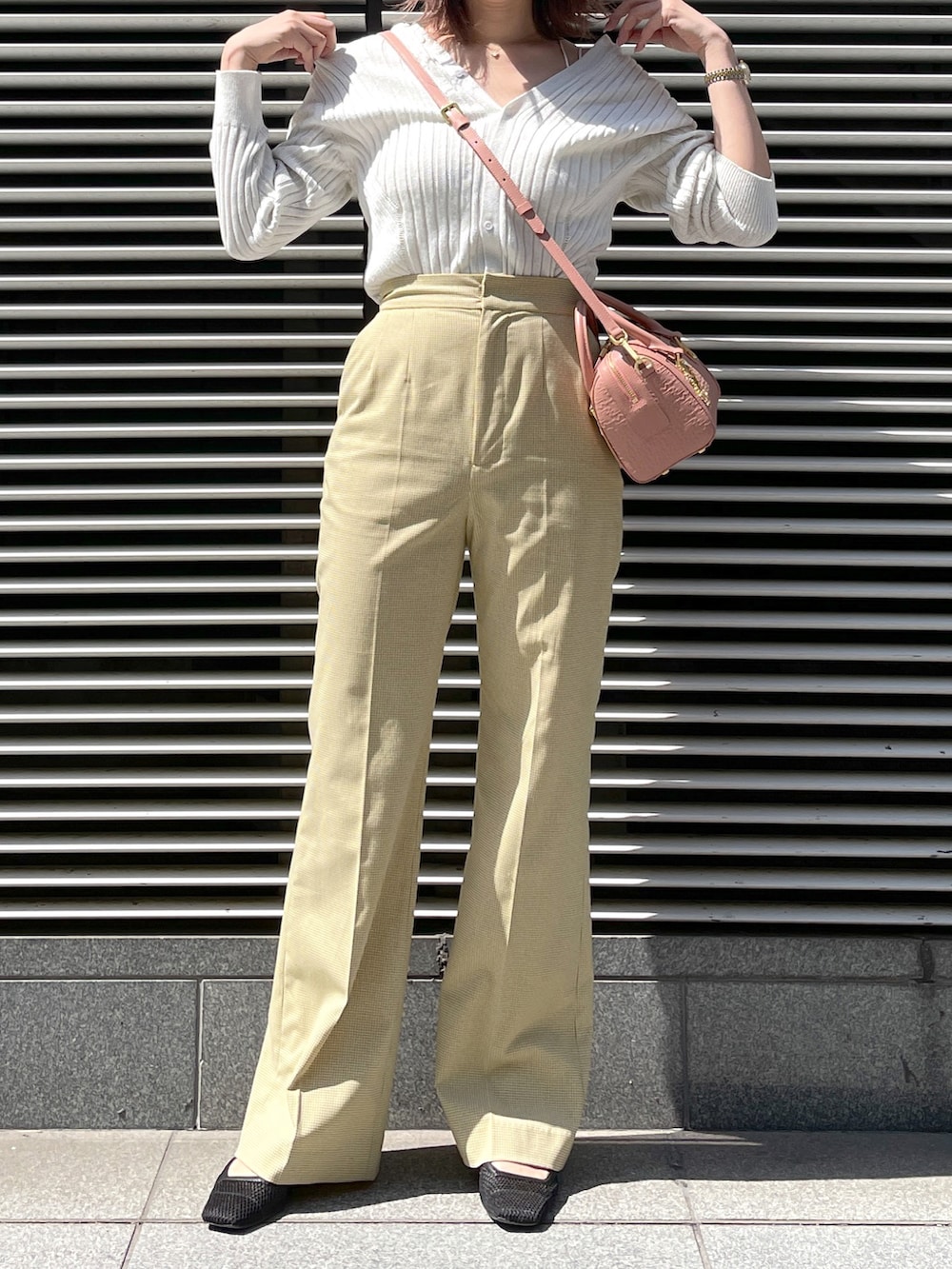 イエロー系のパンツ、ピンク系のショルダーバッグ、シルバー系のトップスを着用したレディースの春コーディネートの2枚目の写真