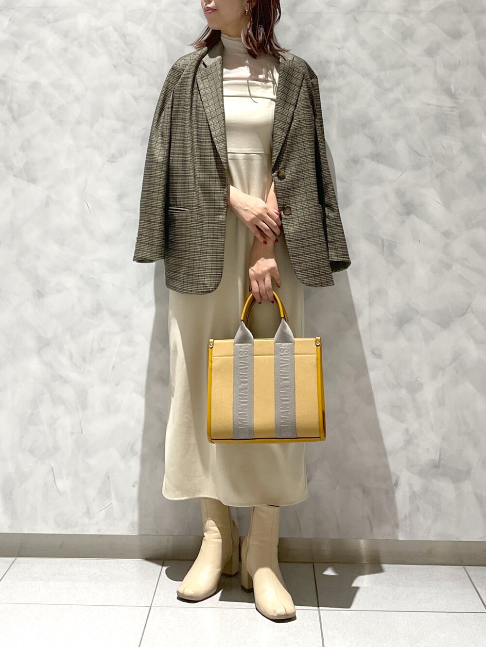 イエロー系のトートバッグ、ブラウン系のテーラードジャケットを着用したレディースの冬コーディネートの2枚目の写真