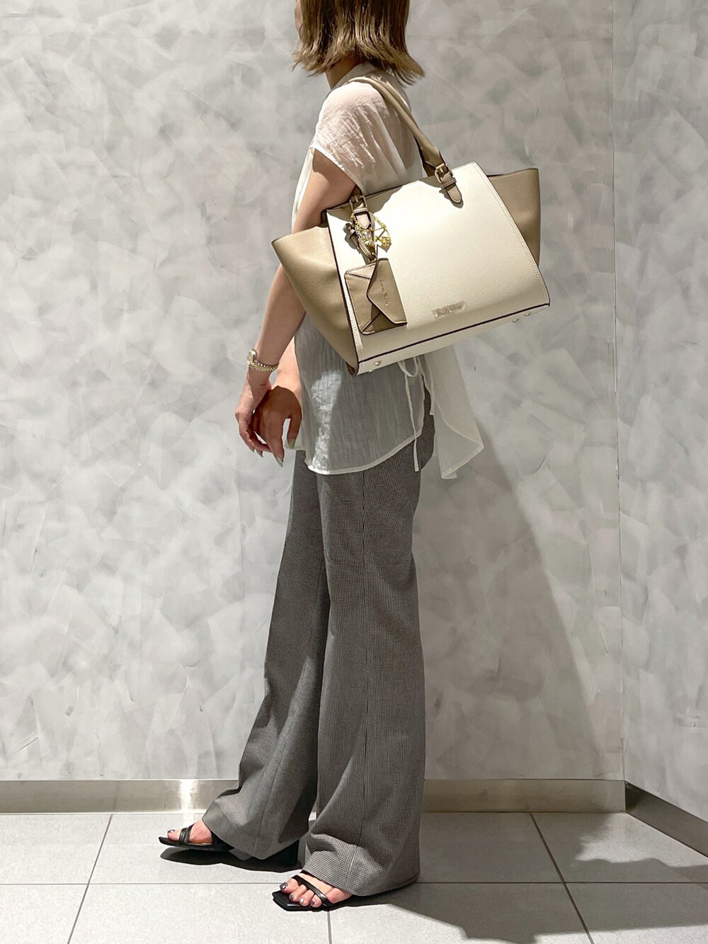 ベージュ系のハンドバッグを着用したレディースの夏コーディネートの3枚目の写真