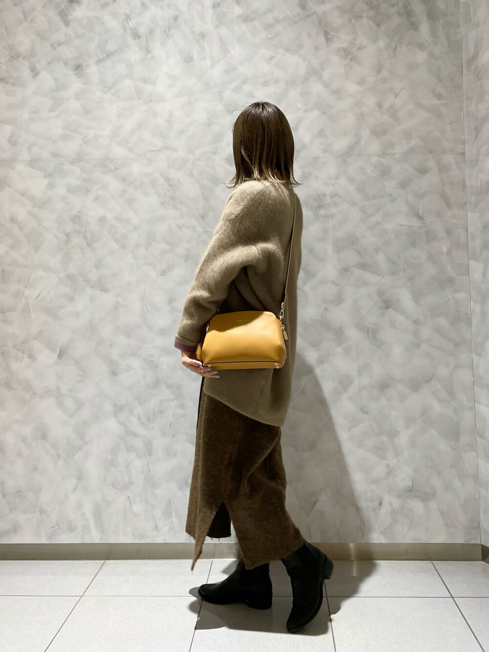 イエロー系のショルダーバッグ、ベージュ系のカーディガン/ボレロ、ブラウン系のワンピースを着用したレディースの冬コーディネートの3枚目の写真