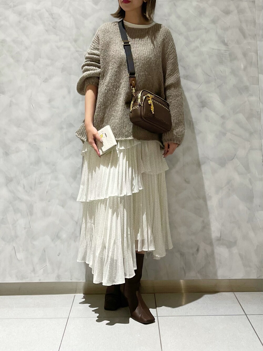 ブラウン系のブーツ、ホワイト系のスカート、ベージュ系のニット/セーターを着用したレディースの冬コーディネートの5枚目の写真