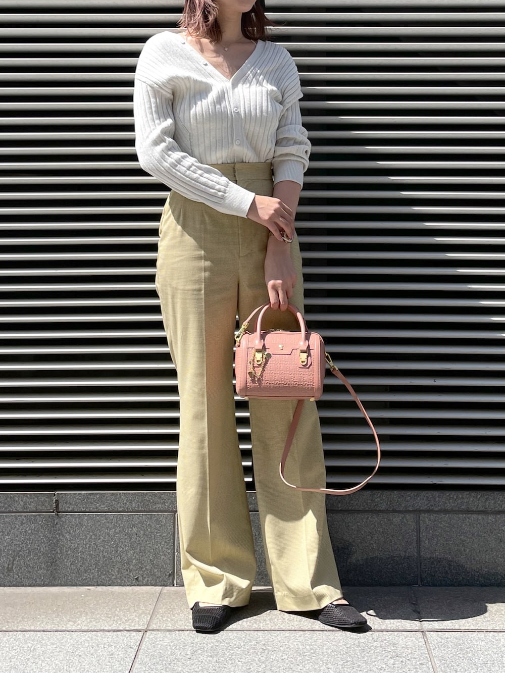 イエロー系のパンツ、ピンク系のショルダーバッグ、シルバー系のトップスを着用したレディースの春コーディネートの3枚目の写真