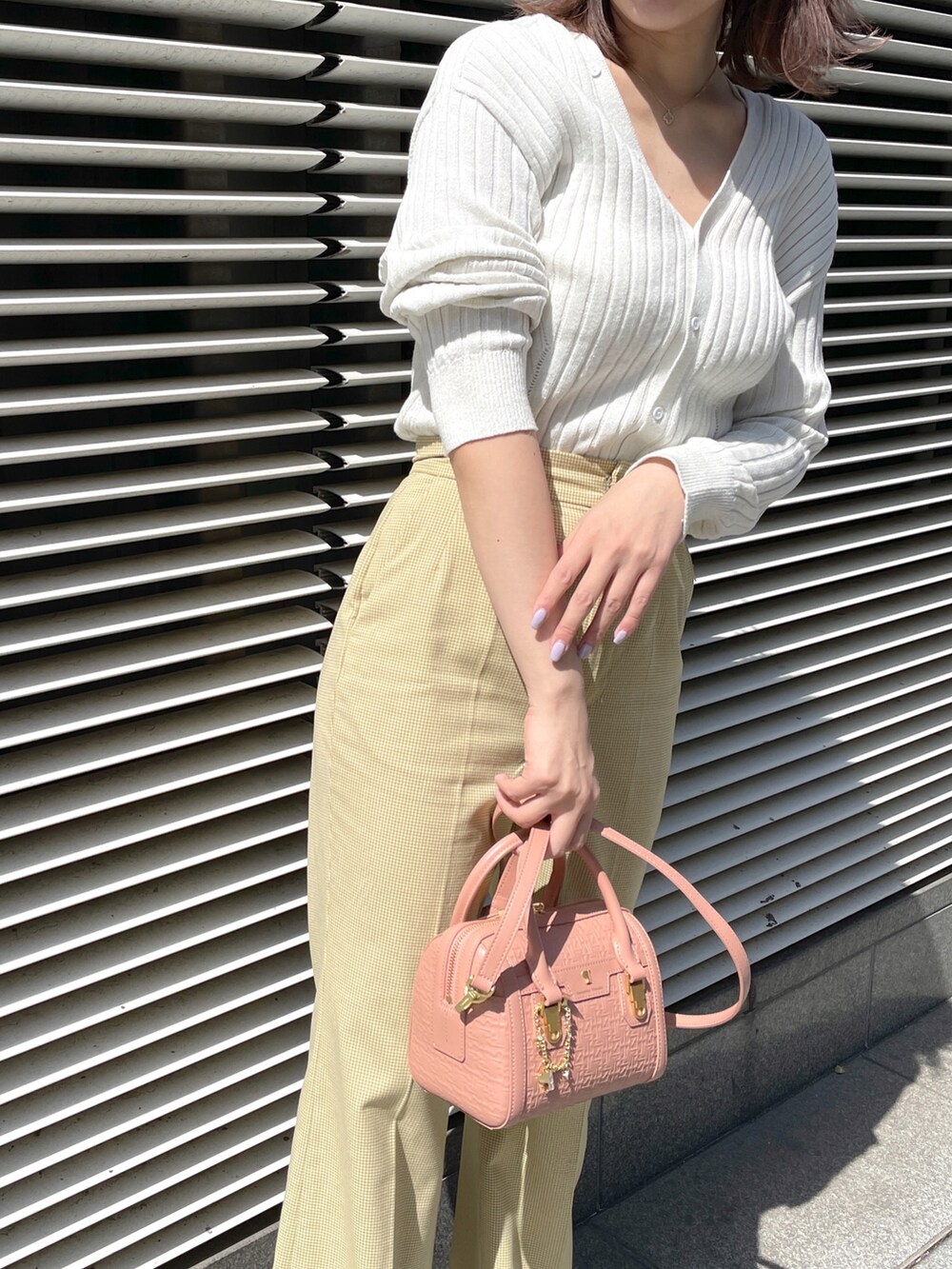 イエロー系のパンツ、ピンク系のショルダーバッグ、シルバー系のトップスを着用したレディースの春コーディネートの5枚目の写真