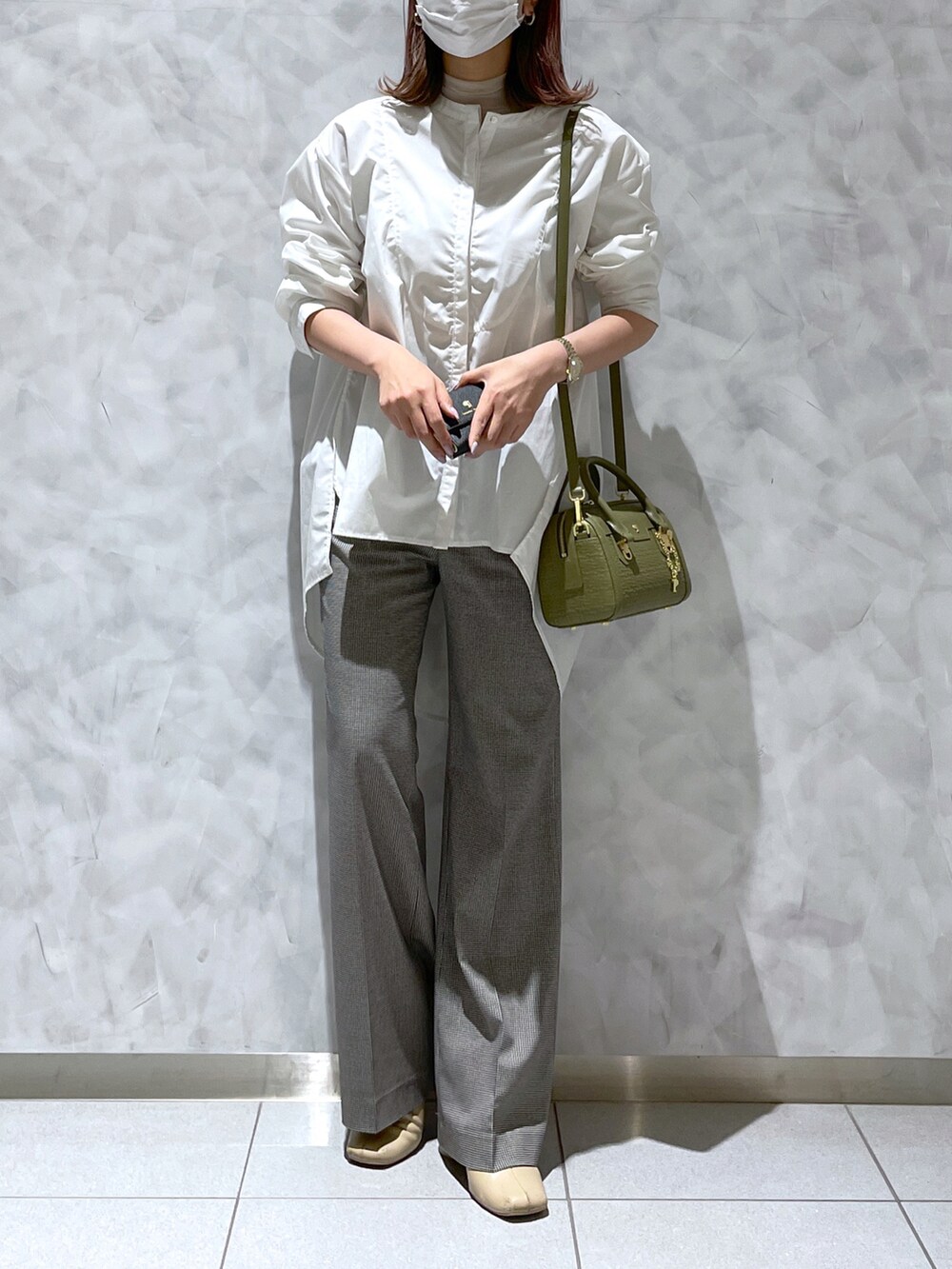 ブラック系のパンツ、グリーン系のショルダーバッグ、ブラック系の財布を着用したレディースの春コーディネートの2枚目の写真