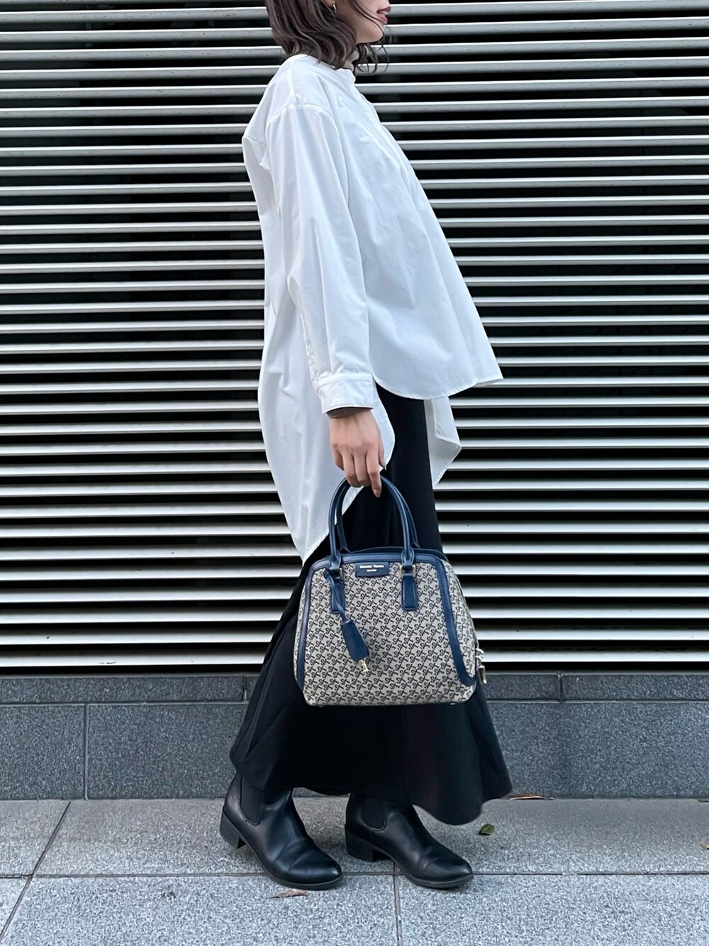 ブラウン系のハンドバッグ、ホワイト系のシャツ/ブラウス、ブラック系のスカートを着用したレディースの冬コーディネートの2枚目の写真