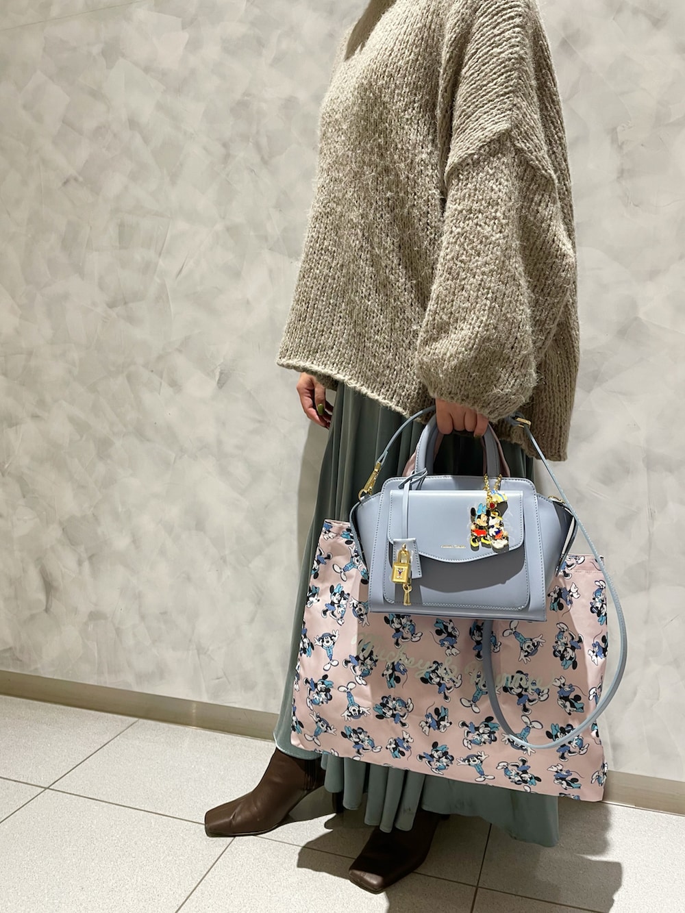 ピンク系のハンドバッグ、ブルー系のハンドバッグ、グリーン系のスカートを着用したレディースの秋コーディネートの4枚目の写真