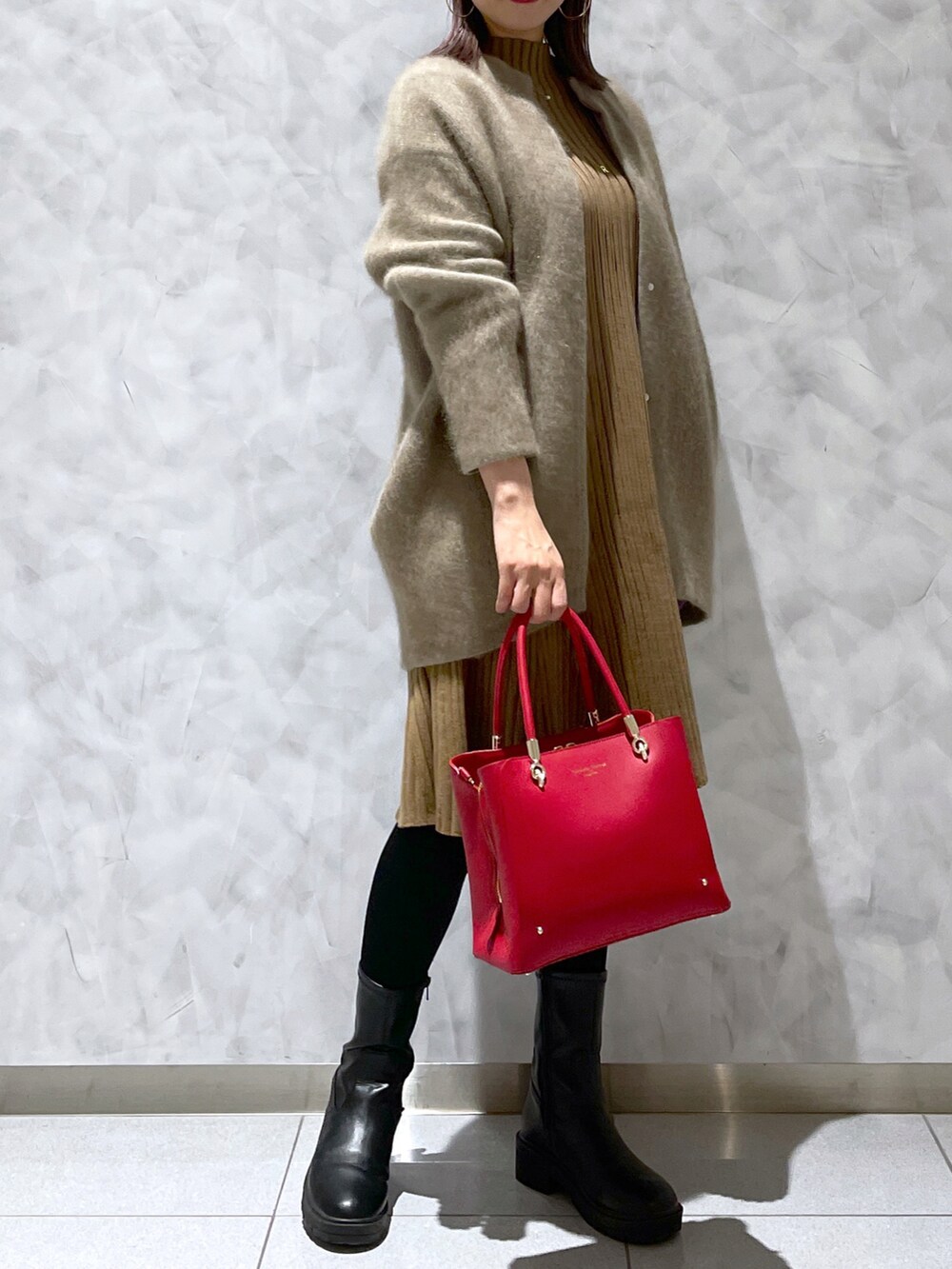 レッド系のトートバッグ、ブラック系のブーツ、ブラウン系のワンピース/ドレスを着用したレディースの冬コーディネートの2枚目の写真