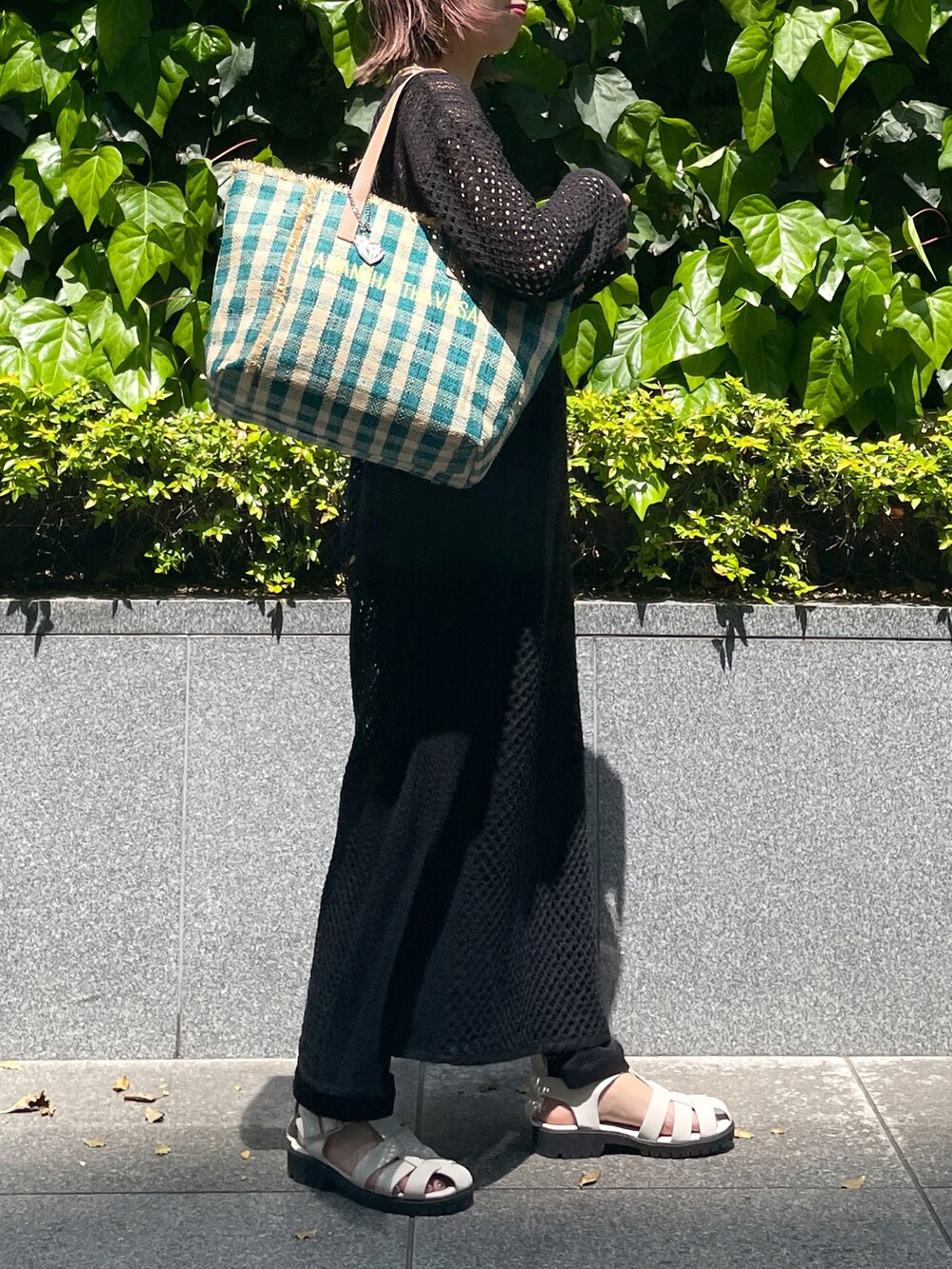 グリーン系のトートバッグ、ブラック系のワンピース、ブラック系のサンダルを着用したレディースの春コーディネートの2枚目の写真
