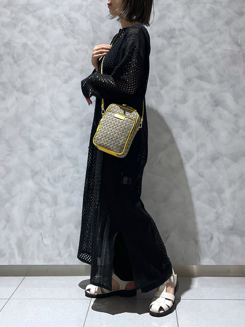イエロー系のショルダーバッグ、ブラック系のワンピース/ドレスを着用したレディースの夏コーディネートの2枚目の写真