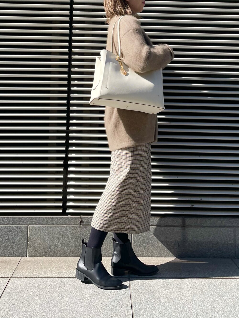 ホワイト系のトートバッグ、ベージュ系のカーディガン/ボレロ、ベージュ系のニット/セーターを着用したレディースの冬コーディネートの2枚目の写真