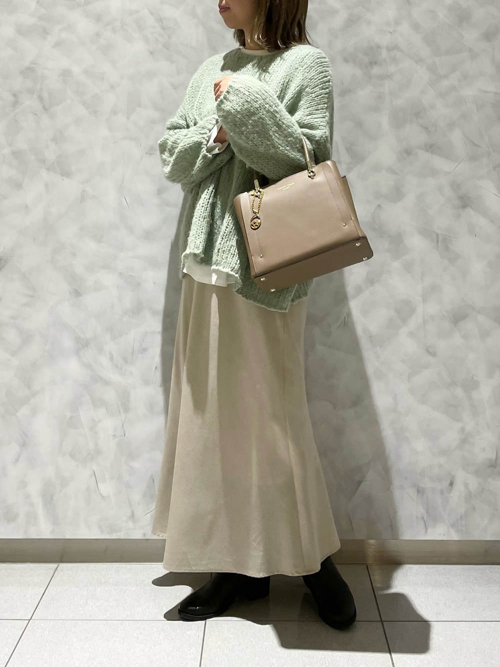 ベージュ系のトートバッグ、グリーン系のニット/セーターを着用したレディースの冬コーディネートの2枚目の写真