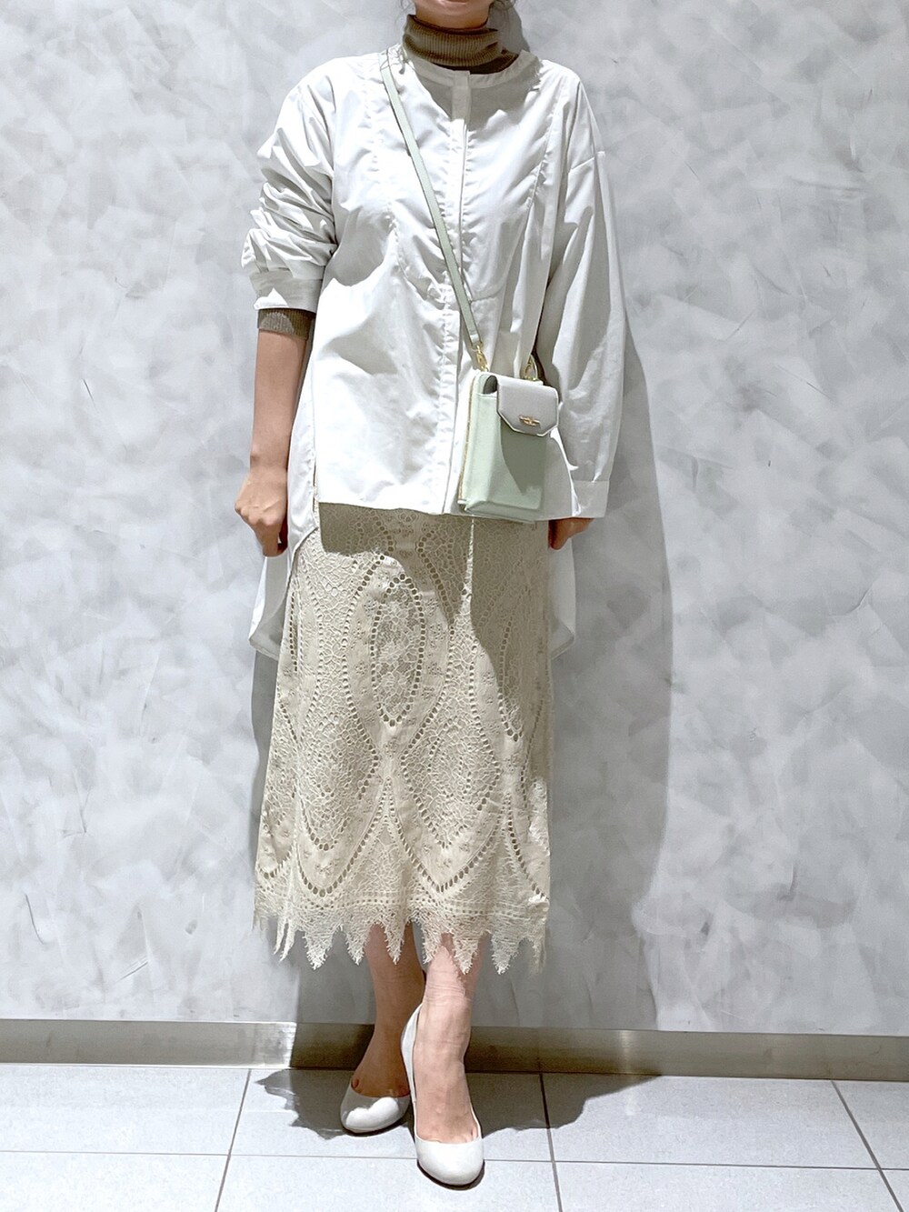 ホワイト系のスカート、グリーン系のショルダーバッグを着用したレディースの冬コーディネートの2枚目の写真