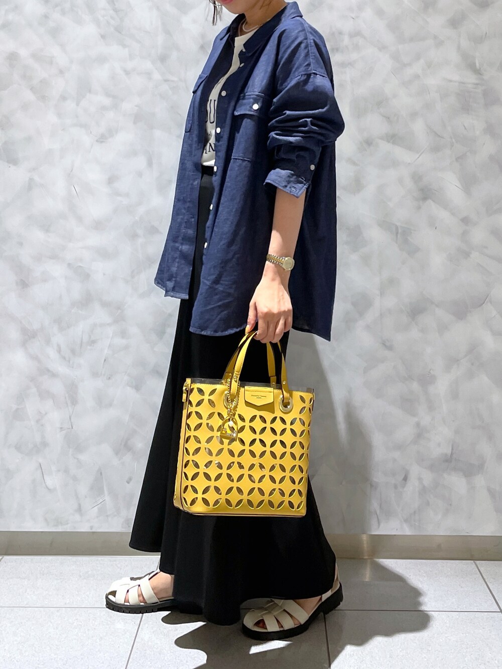イエロー系のトートバッグ、ブラック系のサンダル、ブルー系のデニムジャケットを着用したレディースの夏コーディネートの2枚目の写真