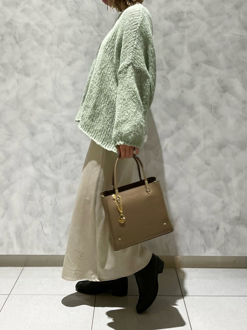 ベージュ系のトートバッグ、グリーン系のニット/セーターを着用したレディースの冬コーディネートの3枚目の写真