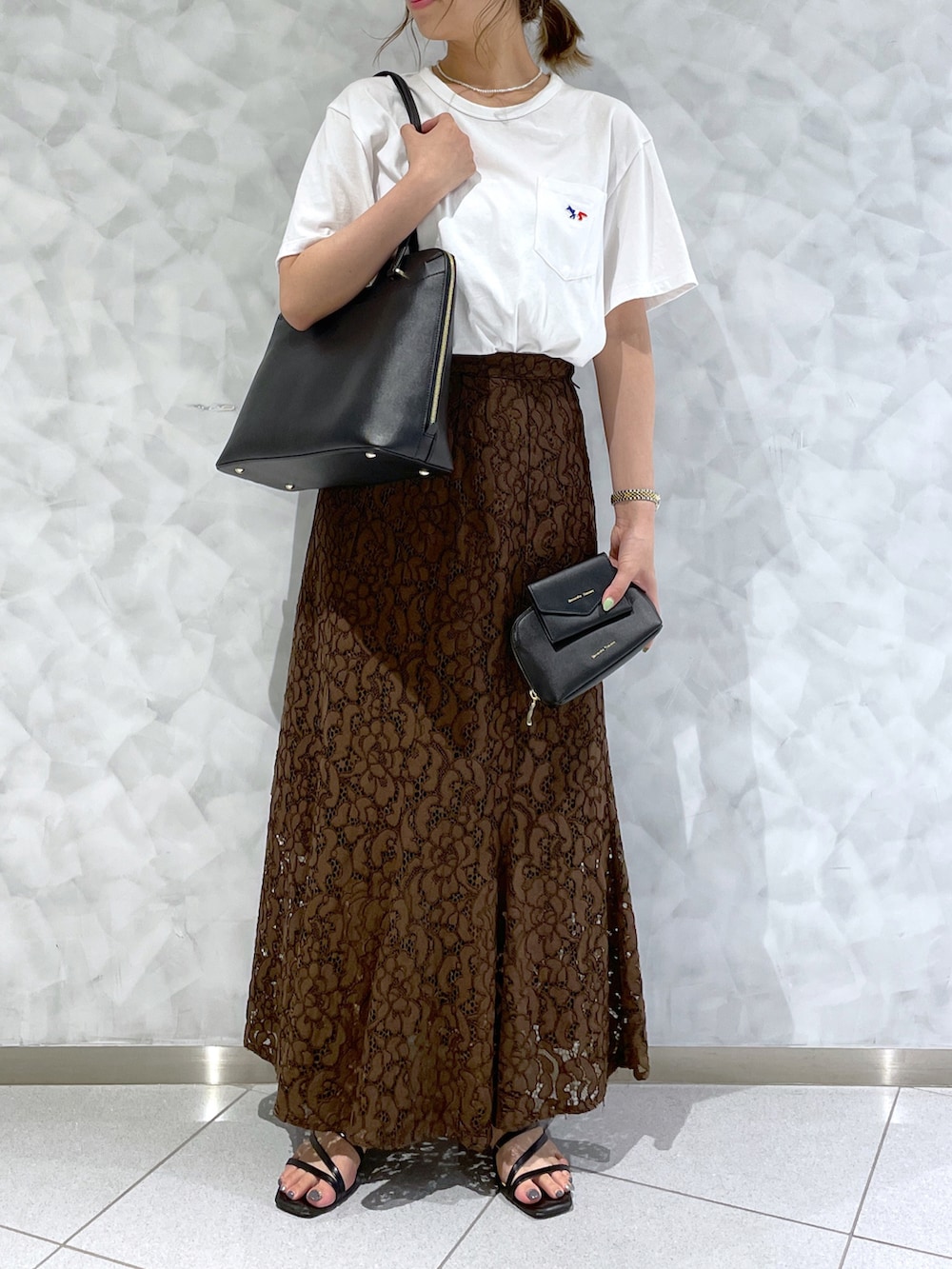 ブラック系のトートバッグ、ブラウン系のスカート、ホワイト系のTシャツ/カットソーを着用したレディースの夏コーディネートの2枚目の写真
