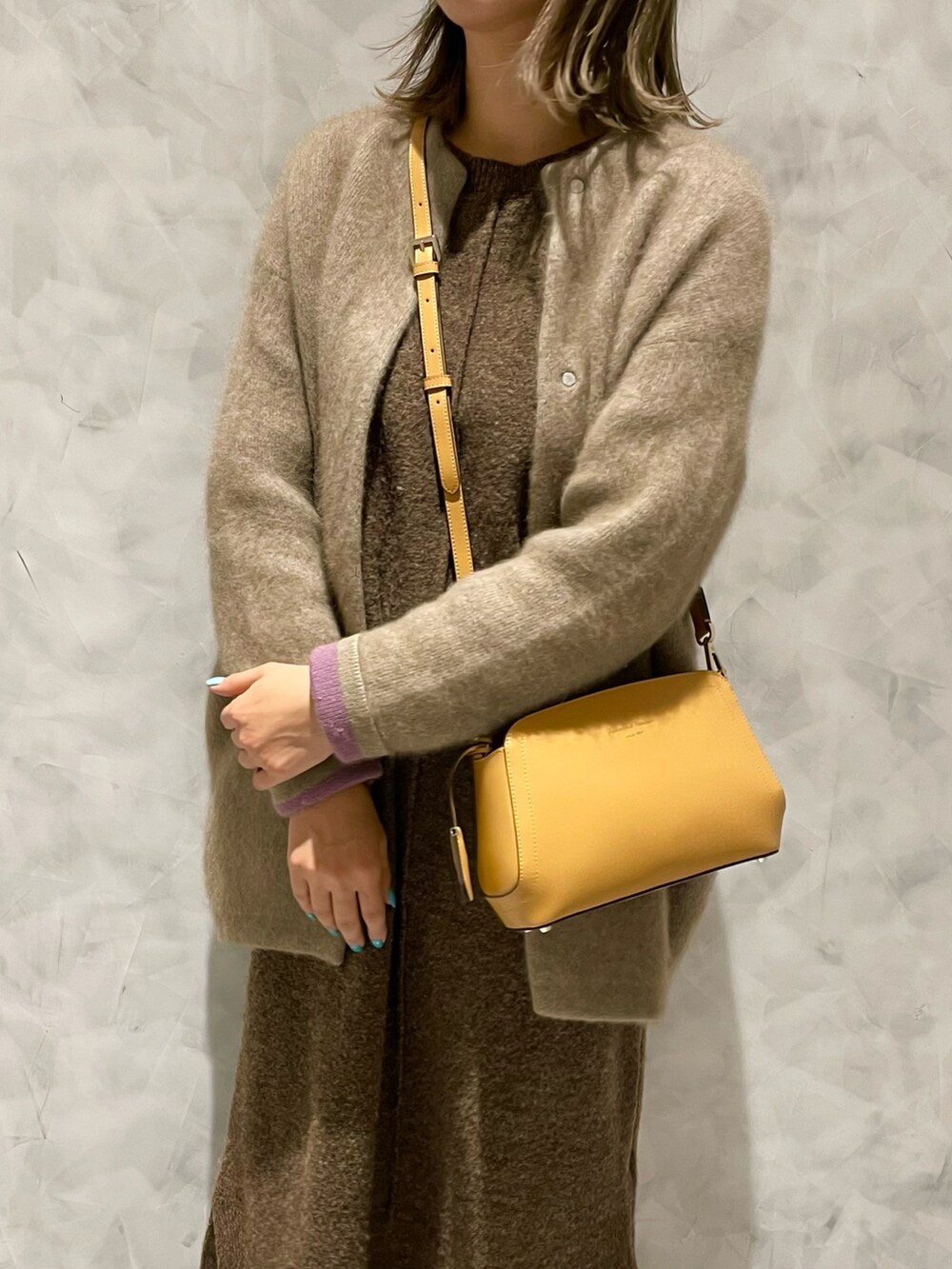 イエロー系のショルダーバッグ、ベージュ系のカーディガン/ボレロ、ブラウン系のワンピースを着用したレディースの冬コーディネートの4枚目の写真