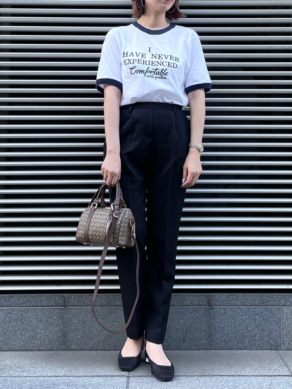 ブラウン系のショルダーバッグ、ブラック系のスラックス、ブルー系のTシャツ/カットソーを着用したレディースの夏コーディネートの2枚目の写真