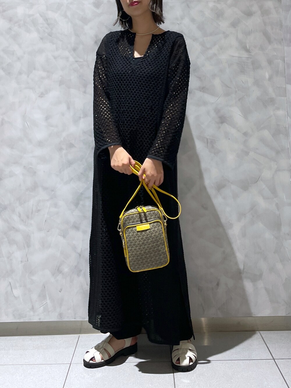 イエロー系のショルダーバッグ、ブラック系のワンピース/ドレスを着用したレディースの夏コーディネートの4枚目の写真