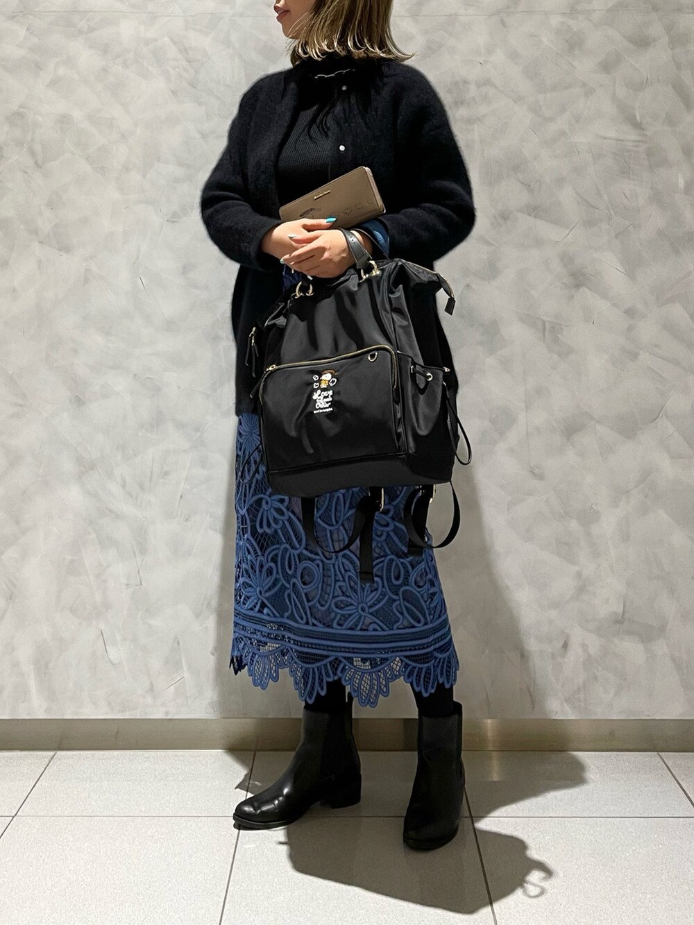 ブルー系のスカート、ブラック系のカーディガン/ボレロ、ブラック系のバックパック/リュックを着用したレディースの冬コーディネートの2枚目の写真