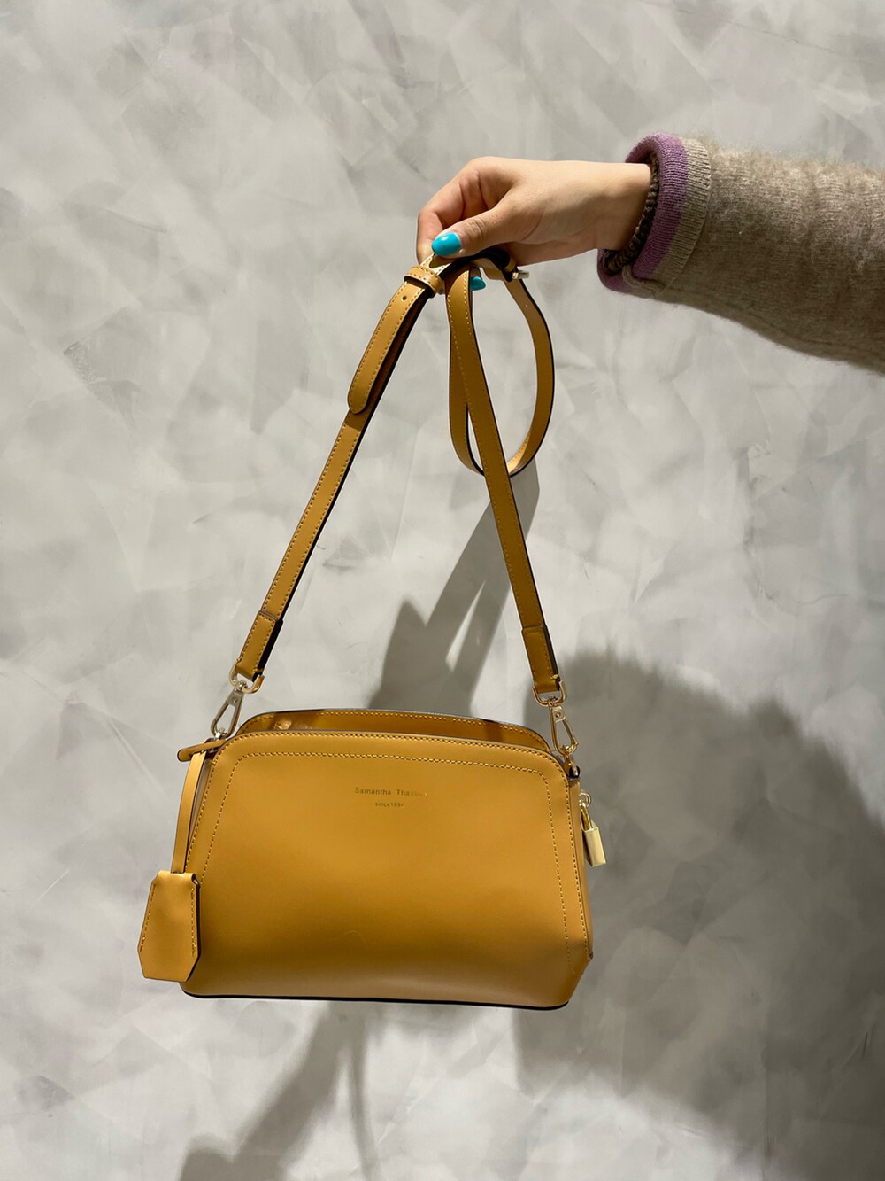 イエロー系のショルダーバッグ、ベージュ系のカーディガン/ボレロ、ブラウン系のワンピースを着用したレディースの冬コーディネートの5枚目の写真