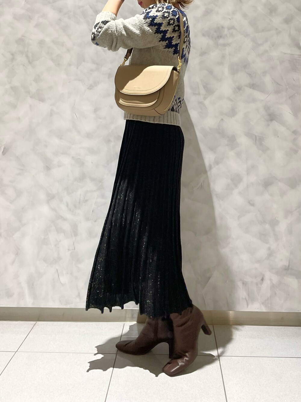 ブラック系のスカート、ベージュ系のショルダーバッグを着用したレディースの冬コーディネートの2枚目の写真