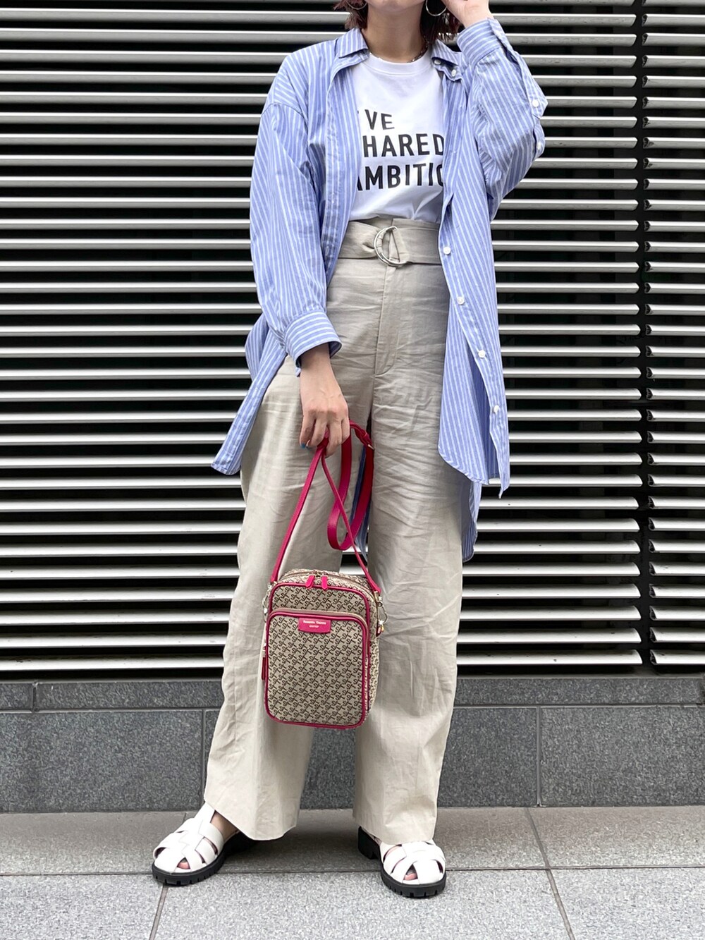 ブラック系のサンダル、ベージュ系のパンツ、ピンク系のショルダーバッグを着用したレディースの春コーディネートの2枚目の写真