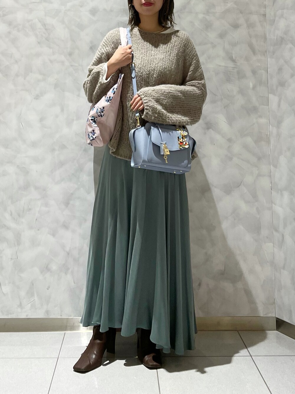 ピンク系のハンドバッグ、ブルー系のハンドバッグ、グリーン系のスカートを着用したレディースの秋コーディネートの3枚目の写真