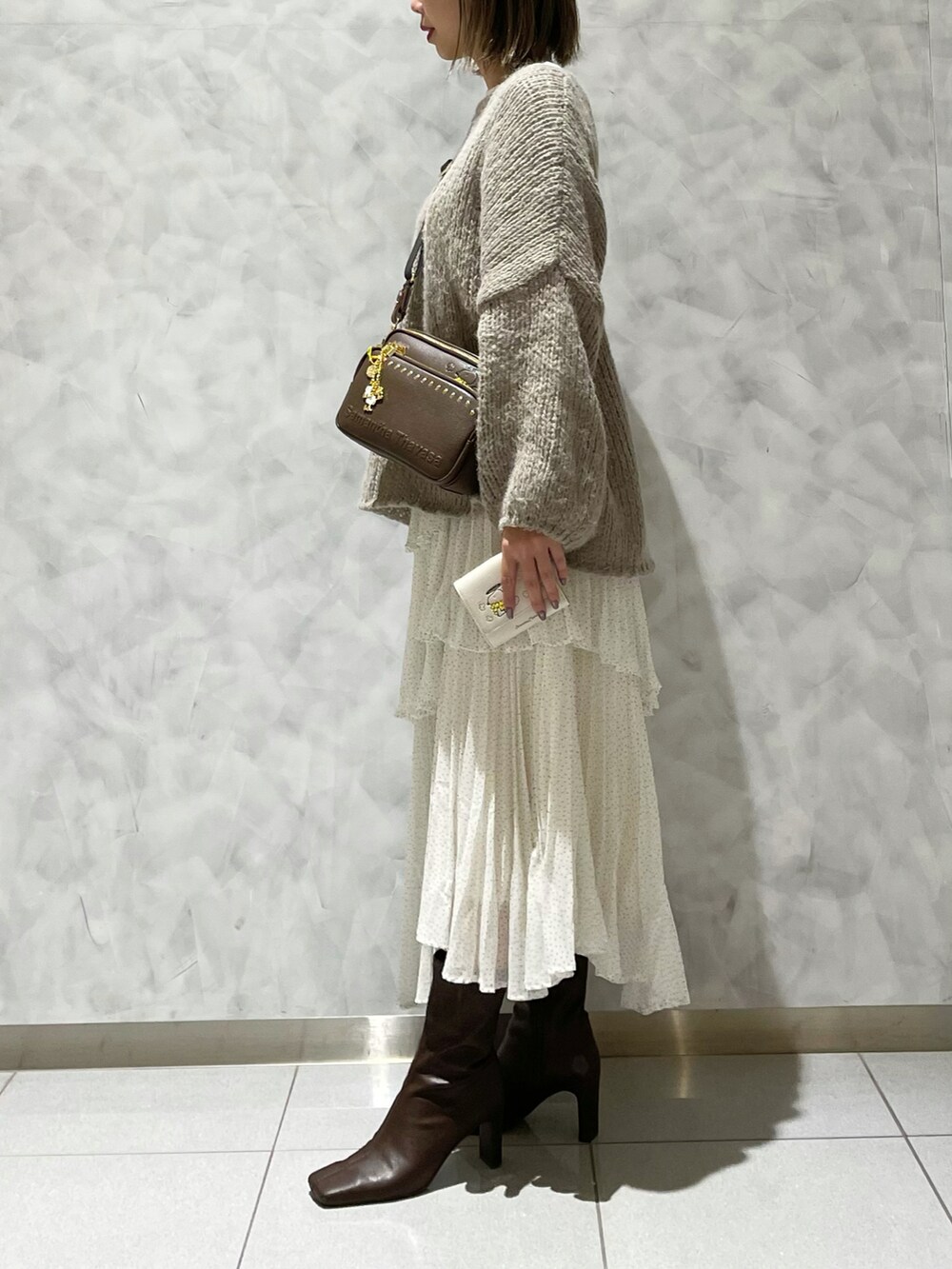 ブラウン系のブーツ、ホワイト系のスカート、ベージュ系のニット/セーターを着用したレディースの冬コーディネートの4枚目の写真
