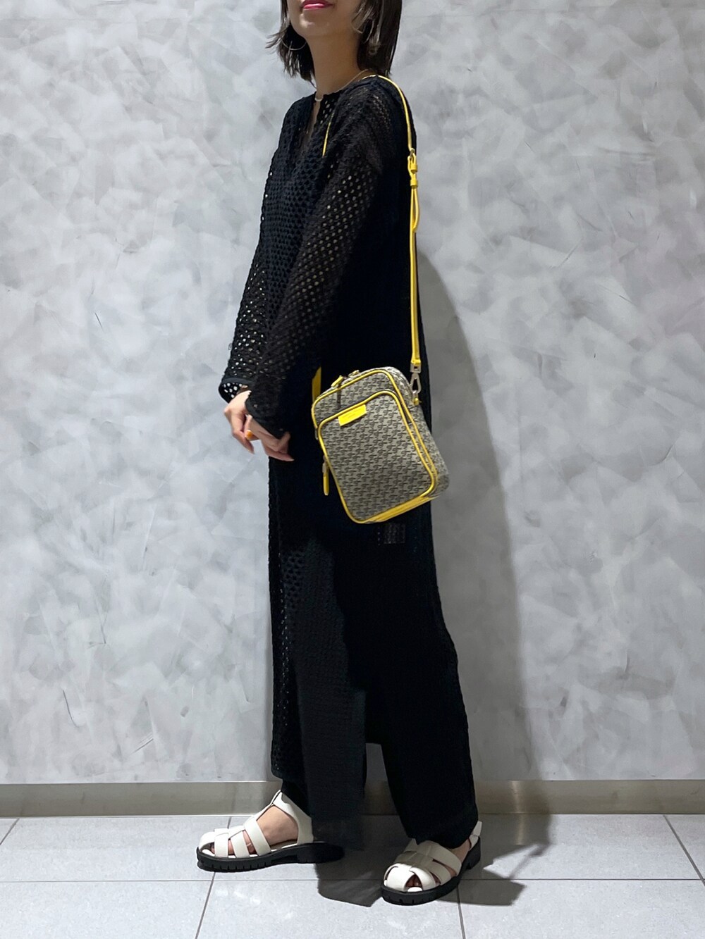 イエロー系のショルダーバッグ、ブラック系のワンピース/ドレスを着用したレディースの夏コーディネートの3枚目の写真