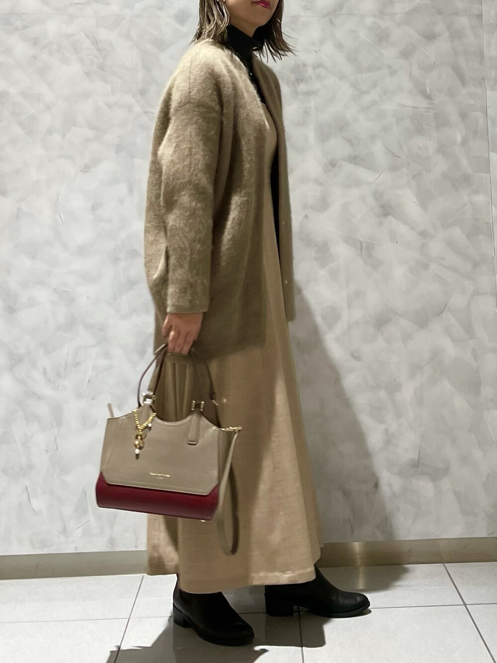 ベージュ系のワンピース/ドレス、ベージュ系のトートバッグ、ベージュ系のカーディガン/ボレロを着用したレディースの冬コーディネートの3枚目の写真