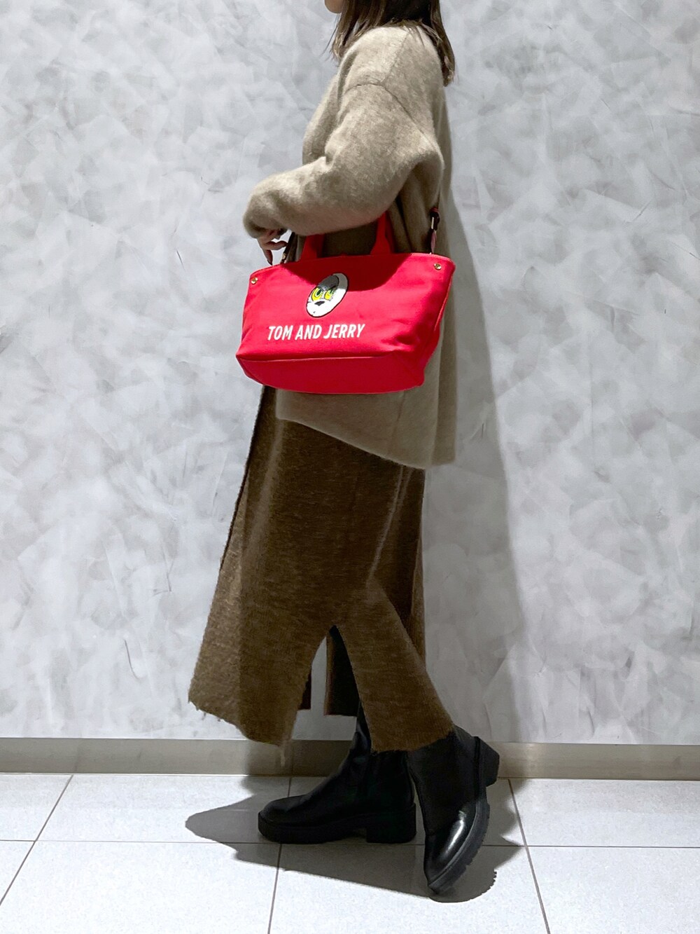 レッド系のトートバッグ、ブラウン系のワンピース、ブラック系のブーツを着用したレディースの冬コーディネートの4枚目の写真