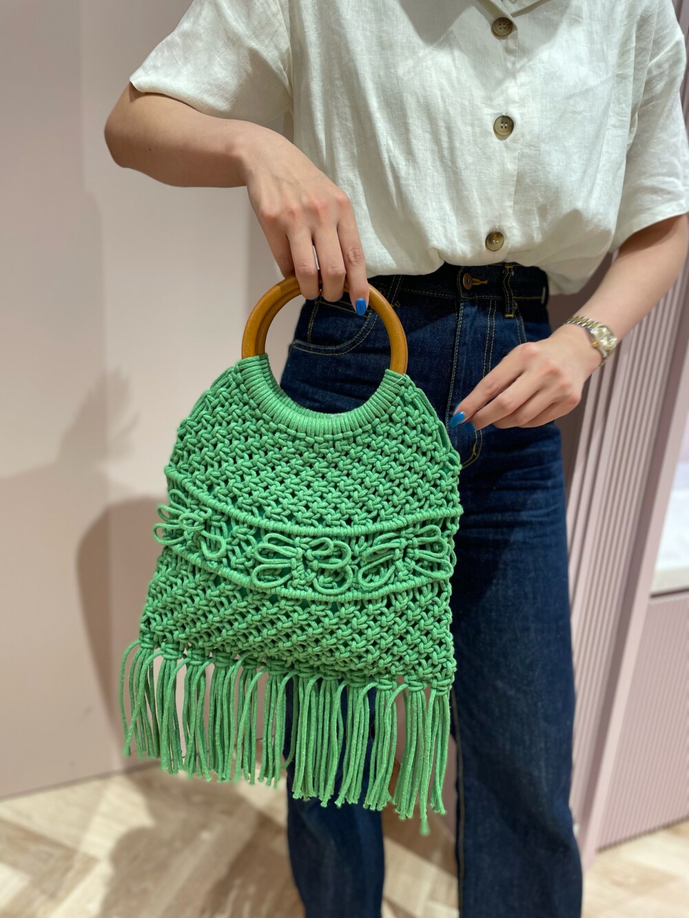 グリーン系のハンドバッグ、ブルー系のデニムパンツ、ベージュ系のサンダルを着用したレディースの夏コーディネートの2枚目の写真