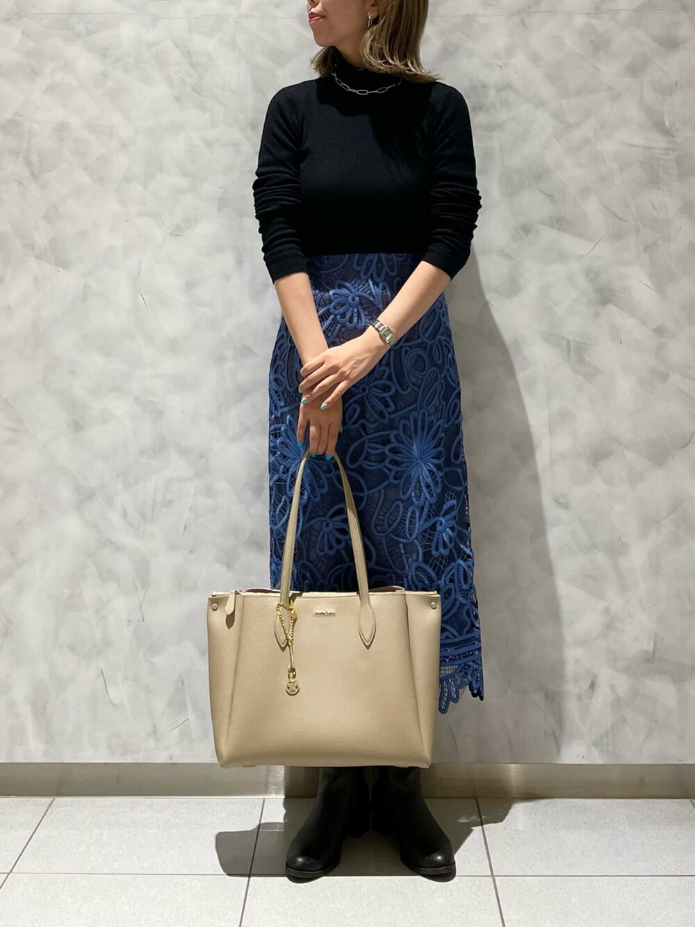 ベージュ系のトートバッグ、ブルー系のスカート、ブラック系のニット/セーターを着用したレディースの冬コーディネートの4枚目の写真