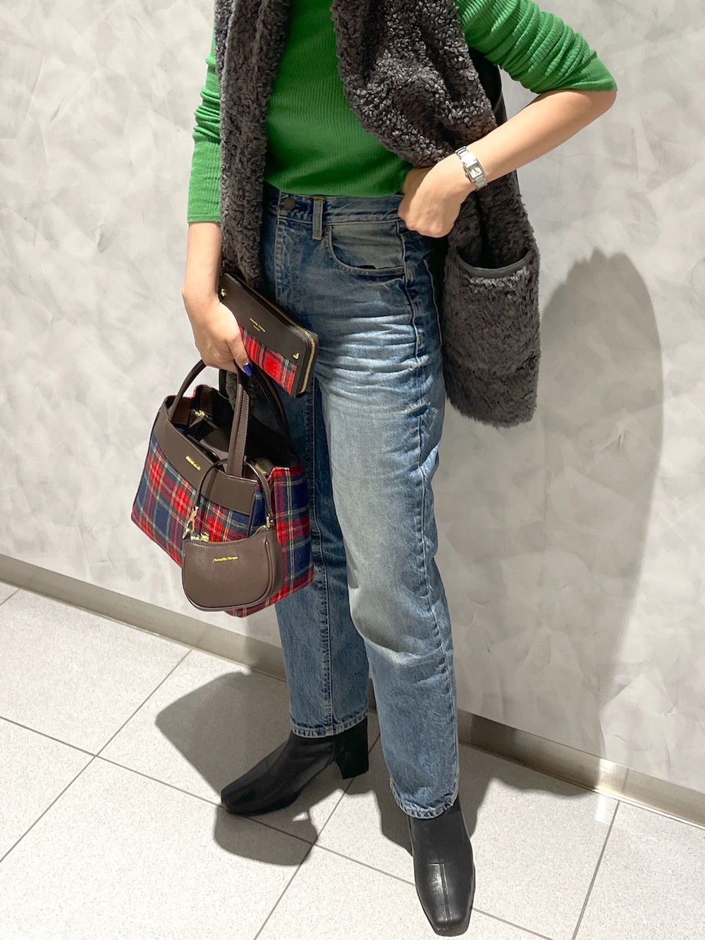 ブルー系のバッグ、グリーン系のニット/セーター、グレー系のベストを着用したレディースの秋コーディネートの2枚目の写真