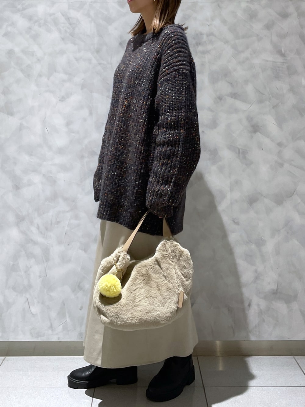 ブラック系のニット/セーター、ベージュ系のトートバッグを着用したレディースの秋コーディネートの2枚目の写真