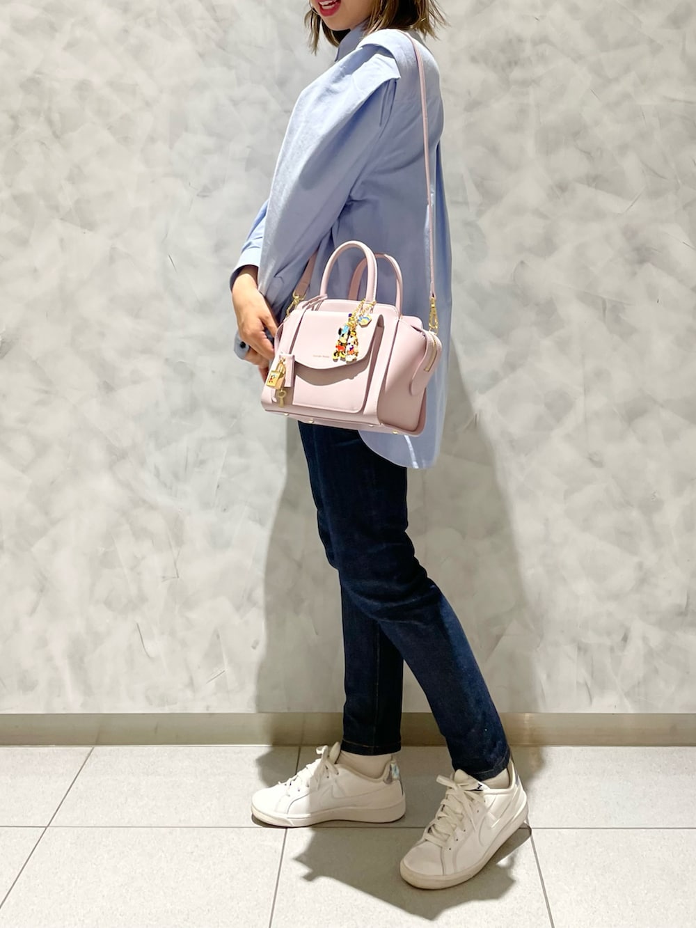 ピンク系のハンドバッグ、ブルー系のデニムパンツを着用したレディースの冬コーディネートの2枚目の写真