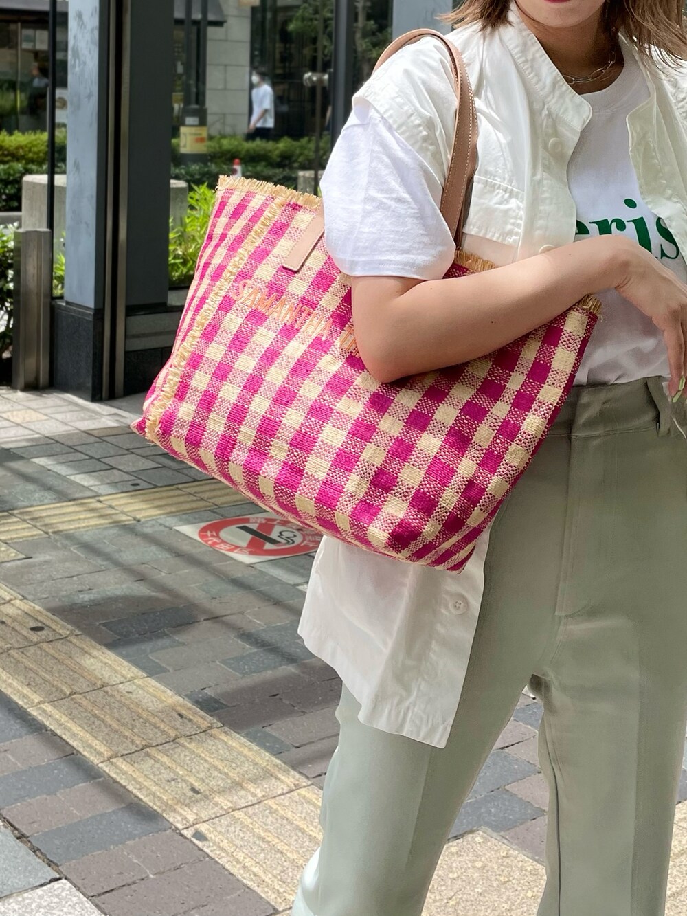 ピンク系のトートバッグ、ホワイト系のベスト、グリーン系のTシャツ/カットソーを着用したレディースの夏コーディネートの3枚目の写真