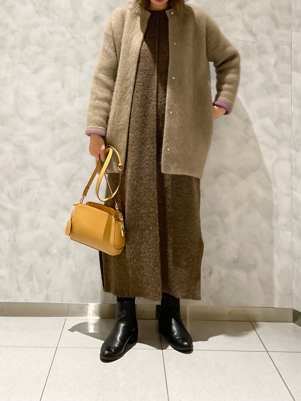 イエロー系のショルダーバッグ、ベージュ系のカーディガン/ボレロ、ブラウン系のワンピースを着用したレディースの冬コーディネートの2枚目の写真