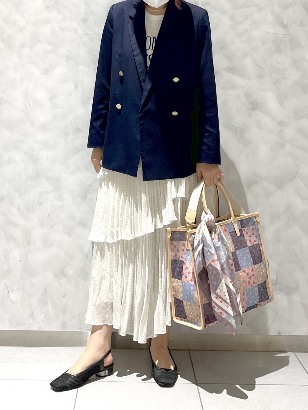 ブラウン系のトートバッグ、ホワイト系のスカート、ブルー系のテーラードジャケットを着用したレディースの春コーディネートの2枚目の写真