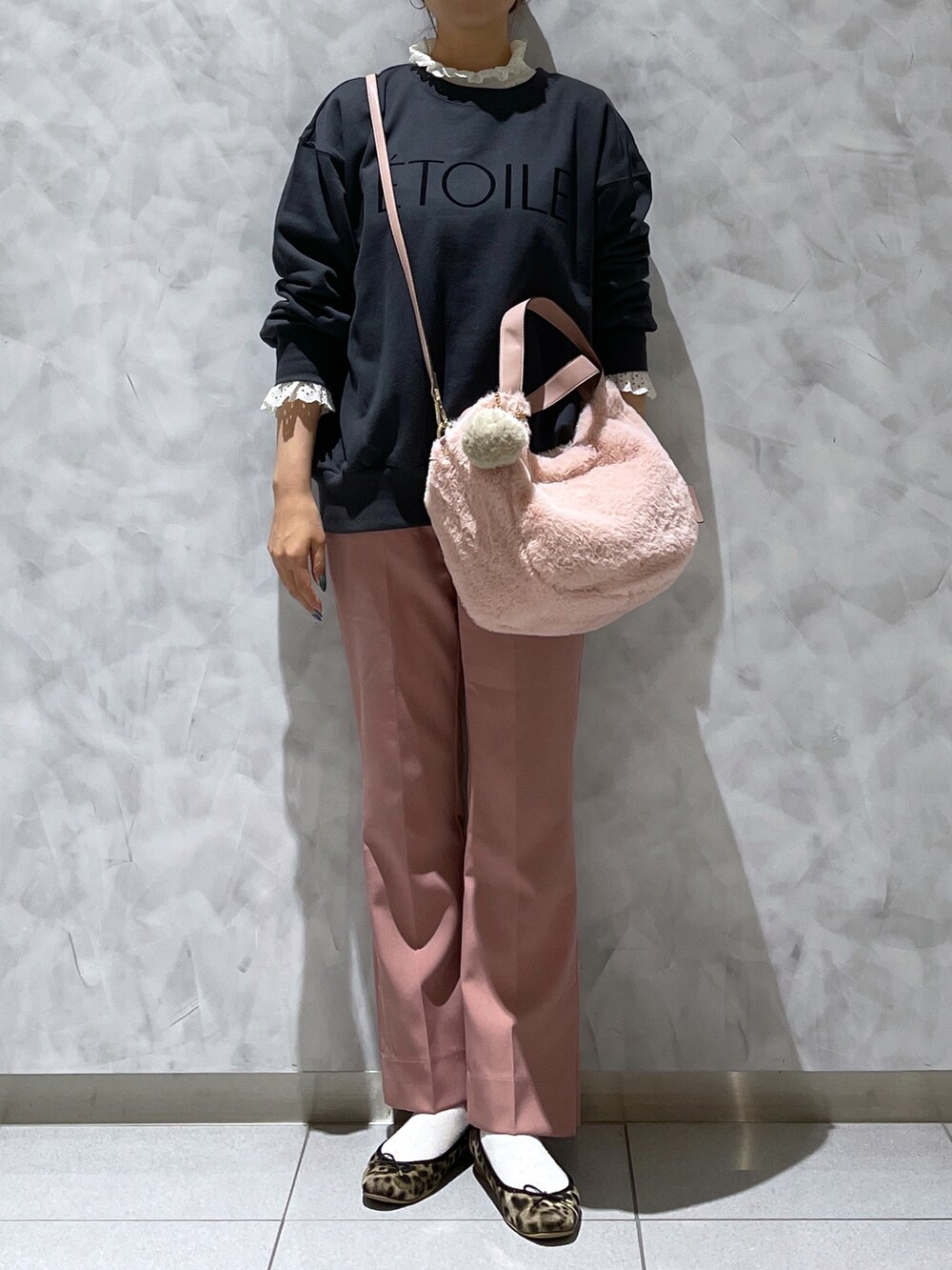 ピンク系のトートバッグ、ブラウン系のシューズ、ブラック系のトップスを着用したレディースの冬コーディネートの2枚目の写真