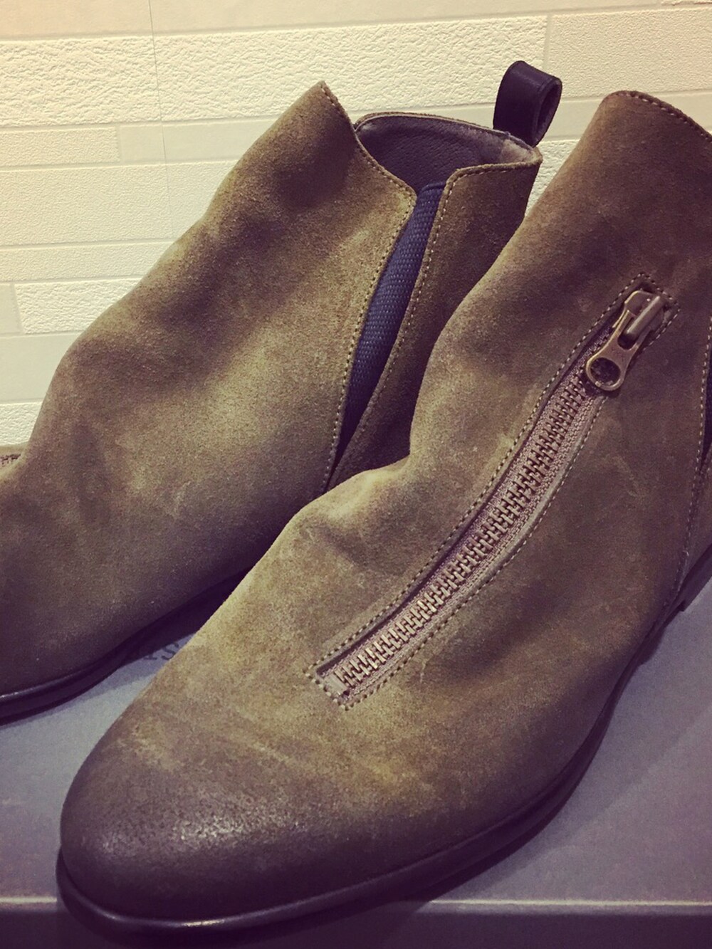 ベージュ系のチェスターコート、グリーン系のニット/セーター、グリーン系のブーツを着用したメンズの冬コーディネートの4枚目の写真