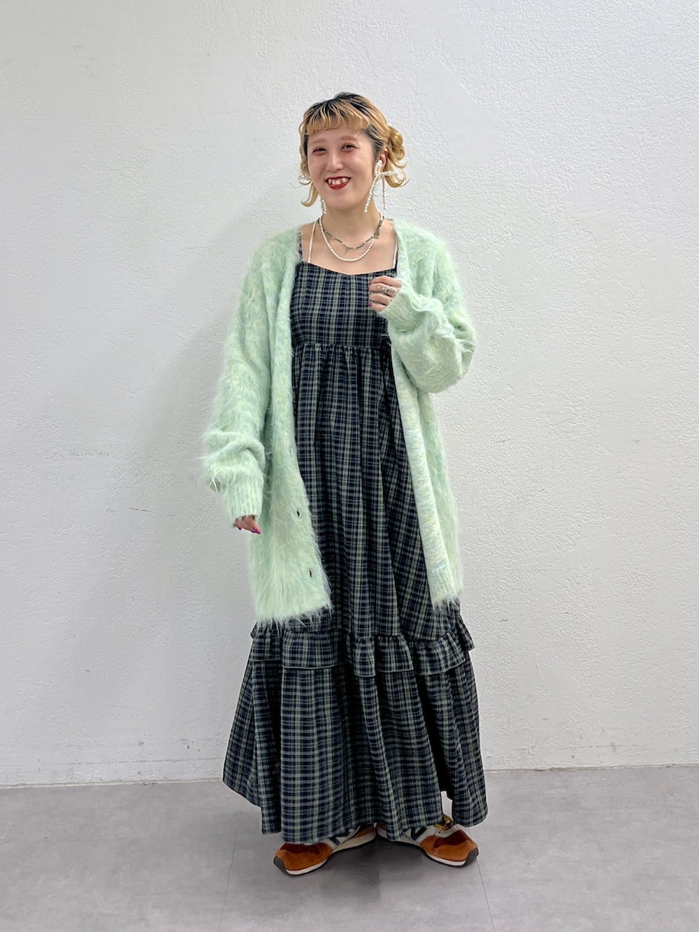 グリーン系のワンピース、ブルー系のカーディガン/ボレロ、オレンジ系のスニーカーを着用したレディースの秋コーディネートの2枚目の写真