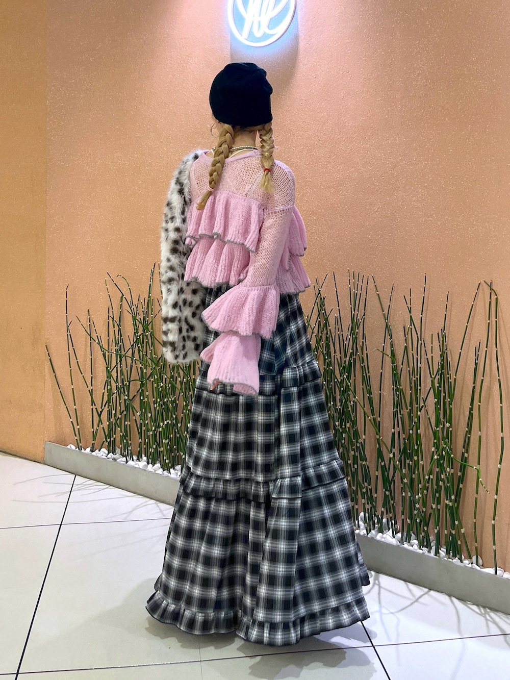 ブラック系のスカート、ピンク系のニット/セーター、ホワイト系のスニーカーを着用したレディースの秋コーディネートの3枚目の写真